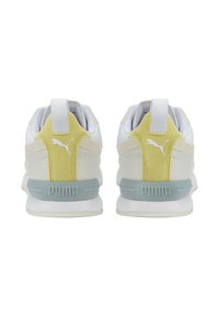 Hvide sneakers med en blød gul ruskinds-accent på hælen, med en lyseblå mellemsål og en trækkrog bagpå. Puma-logoet er vist på hælen.