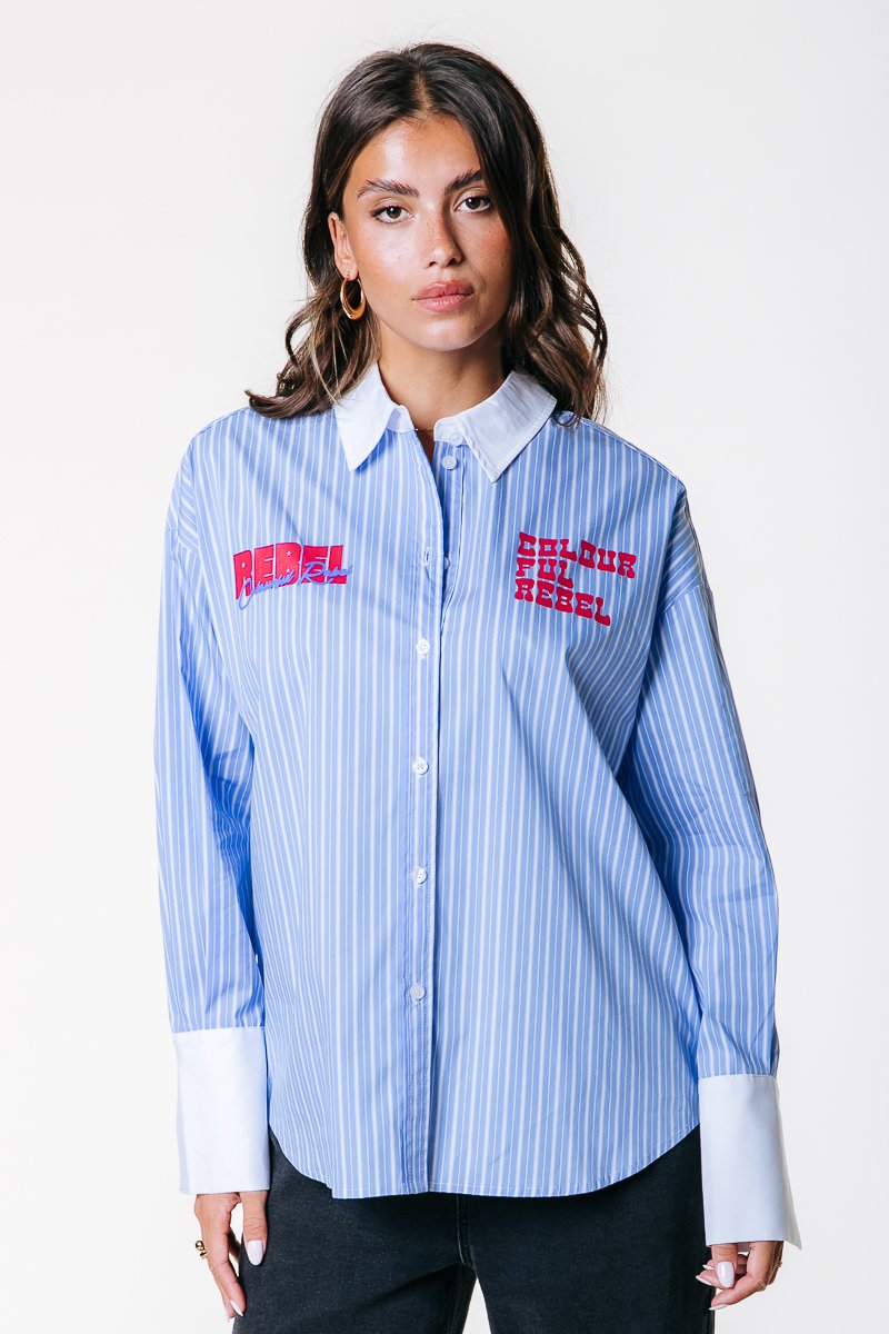 Blauw-wit gestreepte shirt met een knoopsluiting aan de voorkant, witte kraag, grote rode geborduurde tekst "REBEL" en verlengde witte manchet.
