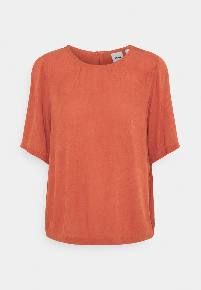 Blusa corta color ruggine a maniche corte con scollo rotondo e chiusura con bottone sul retro, caratterizzata da un tessuto leggero e liscio e una vestibilità rilassata.