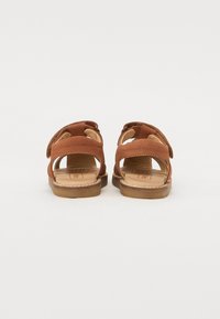 Brune lærsandaler med åben hæl, justerbare stropper, flade såler og et enkelt design med en glat tekstur og minimal syning.