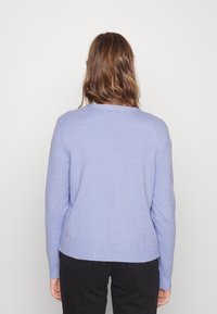 Suéter de color lavanda con cuello redondo y puños acanalados. Textura suave, con un ajuste relajado y color sólido.