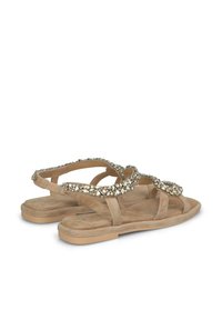 Sandali in suede beige con suola piatta. Presentano accenti decorativi in cristallo lungo le cinghie. Design open-toe e senza retro.