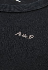 Czarny sweter z dzianiny z okrągłym dekoltem oraz małym, szarym haftowanym logo "A&F" na klatce piersiowej. Miękka tekstura z gładkim wykończeniem.