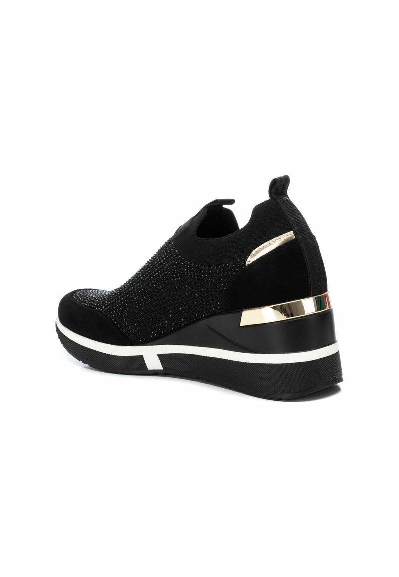Baskets noires avec une tige texturée ornée de strass, un talon compensé rembourré et des accents dorés à l'arrière. Semelle en caoutchouc avec des détails blancs.