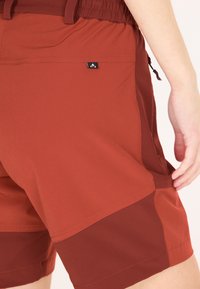 Punaiset shortsit, joissa on sekoitus eri tekstuureja: sileä yläosa ja hieman tummempi alaosa. Sisältää pienen merkkilogon ja taskut.