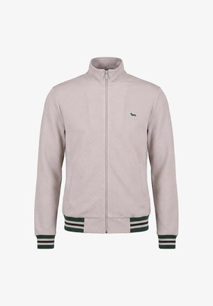 Lysebeige lynlåsjakke med opretstående krave, grønne og hvide stribede ærmeafslutninger og kant samt lille grønt hundelogo på brystet.