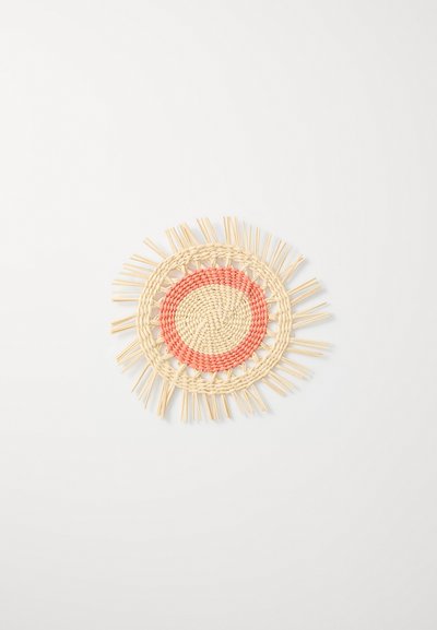 Apvalus pintas kilimėlis, kuriame yra centrinis raudonas apskritimas, apsuptas natūralių šiaudų akcentų, su tekstūruota paviršiumi ir š Fringe kraštu.