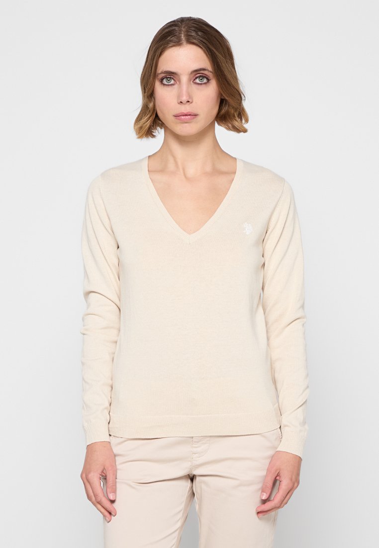 Beige V-hals trui met lange mouwen, gemaakt van zacht materiaal. Beschikt over een geribbelde textuur en een klein logo op de linkerborst.
