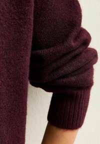 Manica di maglione lavorato a maglia bordeaux caratterizzata da una consistenza morbida e pelosa, con polsino a costine e design morbido e piegato al gomito.