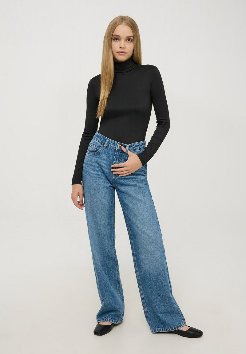 Czarna dopasowana golf, szerokie jasnoniebieskie dżinsy i czarne baleriny. Prosta faktura o minimalnych detalach, podkreślająca casualowy styl.