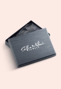 Grå smykkeboks med en tekstureret overflade. Låget er let åbent og afslører sort silkepapir indeni. Hvidt logo: "Sofia Milani JEWELS."
