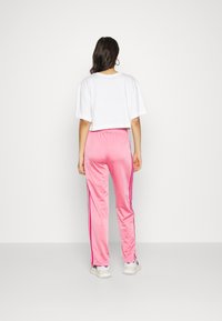Cropped white t-shirt with short sleeves, paired with pink sweatpants featuring side stripes and a soft texture. White sneakers complete the look.