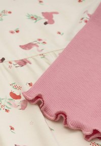 Rosa geripptes Material mit einer Rüsche am Rand, neben einem cremefarbenen Hintergrund mit einem floralen und tierischen Druckmuster.