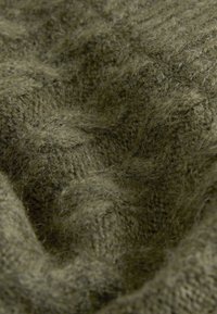 Olive green knitted fabric close-up, showcasing thick, textured fibers with a soft, fuzzy appearance and visible stitching patterns.