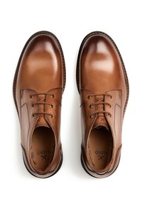 Scarpe in pelle marrone con finitura liscia, dotate di sei occhielli, cuciture a contrasto, punta arrotondata e soletta imbottita.