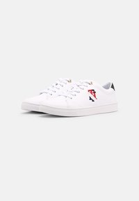 White sneakers made of smooth synthetic material, featuring front laces, a textured rubber sole, and a colorful logo on the side.