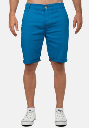 Pantaloni corti in cotone blu con risvolti, cuciture a contrasto rosse e chiusura con bottone. Presenta tasche laterali e posteriori per il deposito.