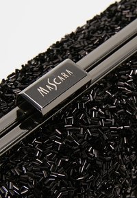 Pochette noire à surface texturée composée de petites perles cylindriques. Dotée d'une fermeture en métal noir brillant gravée du mot "MASCARA".