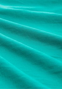 Tessuto turchese con una texture liscia, che mostra pieghe delicate e un colore uniforme, caratterizzato da una leggera qualità riflettente.