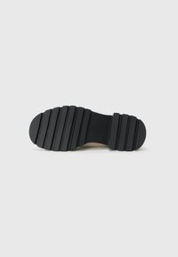 Suela de zapato de goma negra con ranuras horizontales y una puntera redondeada. Presenta una sección lisa cerca de la parte trasera y un acabado texturizado.