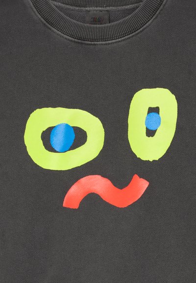 Schwarzer Pullover mit einem grafischen Design, das zwei große grün umrandete Augen, einen blauen Kreis und eine rote gewellte Linie zeigt.