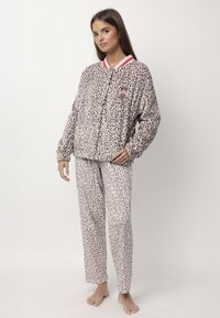 Completo pigiama in stampa leopardata realizzato in morbido tessuto, con maniche lunghe, colletto a righe rosse e polsini elasticizzati, completato da un pantalone stampato coordinato.