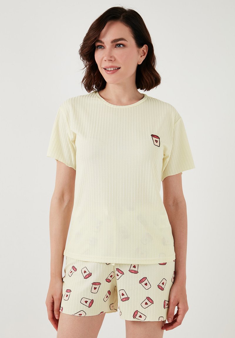 Set de pijama format dintr-un top galben cu maneci scurte, texturat, având un design cu căni mici, și pantaloni scurți crem cu un model care include accente de inimioare pe borcane.