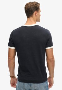 Camiseta de manga corta azul marino con cuello y detalles en las mangas en blanco, hecha de material suave, diseño ajustado y escote redondo.