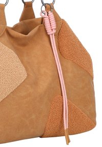 Tan leren handtas met verschillende texturen, met zachte suède-achtige patches en een rozige koordaccent. Versterkte handvatten met metalen ringen.