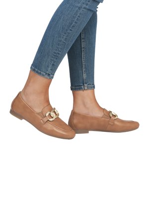 Mocasines de cuero marrón presentan un acento dorado y una textura suave, combinados con jeans ajustados azules. El zapato tiene una suela plana y punta redondeada.