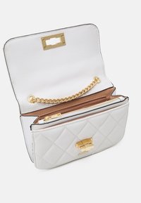 Bílá syntetická taška s prošíváním a zlatými prvky. Obsahuje řetízek, kapsu na zip a magnetické uzavírání. Vnitřek je podšitý hnědou látkou.