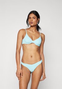 Svijetloplavi bikini set s oblikovanim grudnjakom s podesivim naramenicama i donjim dijelom s niskim strukom, izrađen od glatkog, rastezljivog materijala.