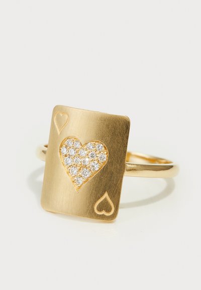Anillo de oro con una cara en forma de cuadrado que presenta un diseño de corazón, adornado con cristales transparentes y pequeños grabados de corazones en los laterales.