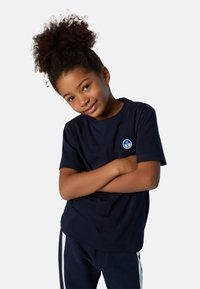 Camiseta de algodón azul marino con manga corta, cuello redondo y un pequeño parche de logo azul y blanco en el área del lado izquierdo del pecho.