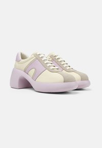 Niedrig geschnittene Sneakers mit einem klobigen Lavendel-Absatz, einem Obermaterial aus beigem Leder, rosa Wildlederakzenten und weißen Schnürsenkeln. Modernes Design mit kontrastierenden Texturen.