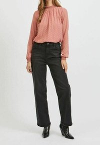 Blusa a maniche lunghe, rosa pallido, con scollatura plissettata e sottile motivo a zigzag, abbinata a jeans neri a vita alta e stivaletti con punta.
