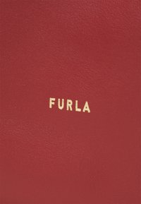 Piros bőr, textúrált felülettel, arany "FURLA" logóval, középen elhelyezve a láthatóság érdekében.