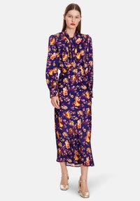 Purple floral dress with long sleeves, tie neck, and mid-length hem. Features bold multicolored flowers on a smooth, silky fabric.