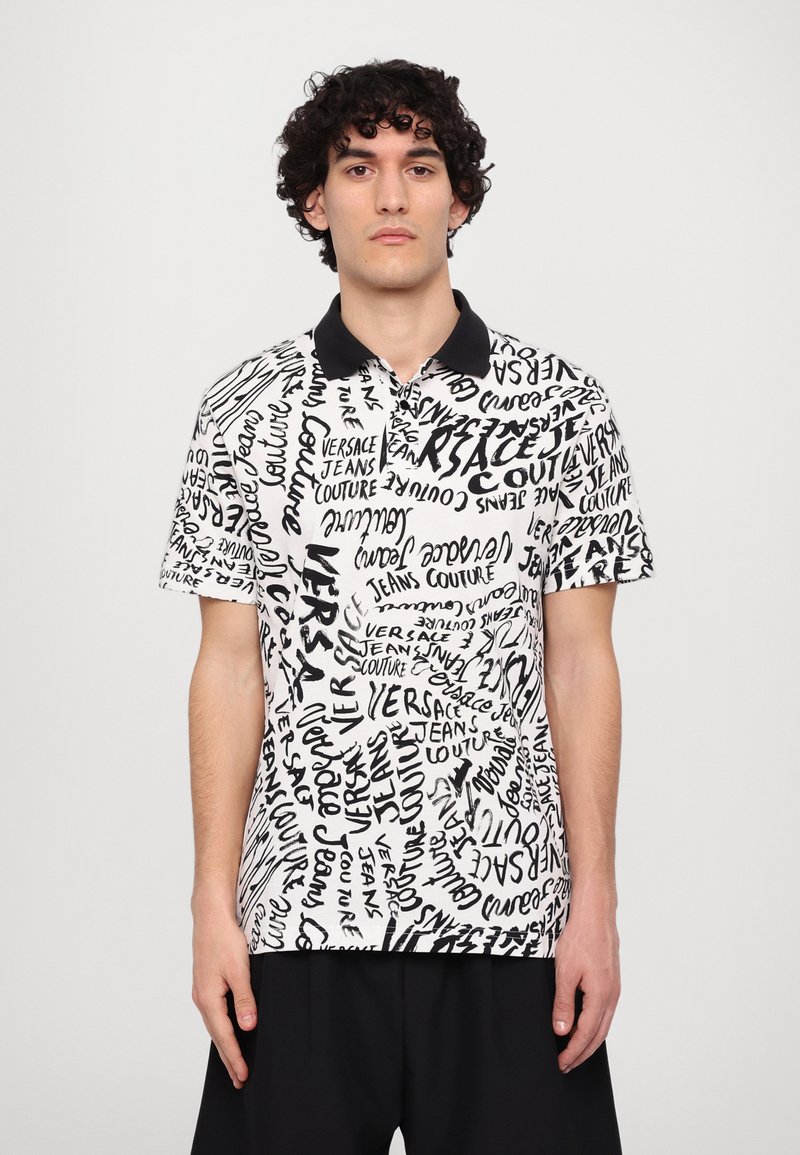 Camisa polo de manga curta com um padrão de texto em preto e branco, gola de malha preta e ajuste relaxado. Feita de tecido leve.