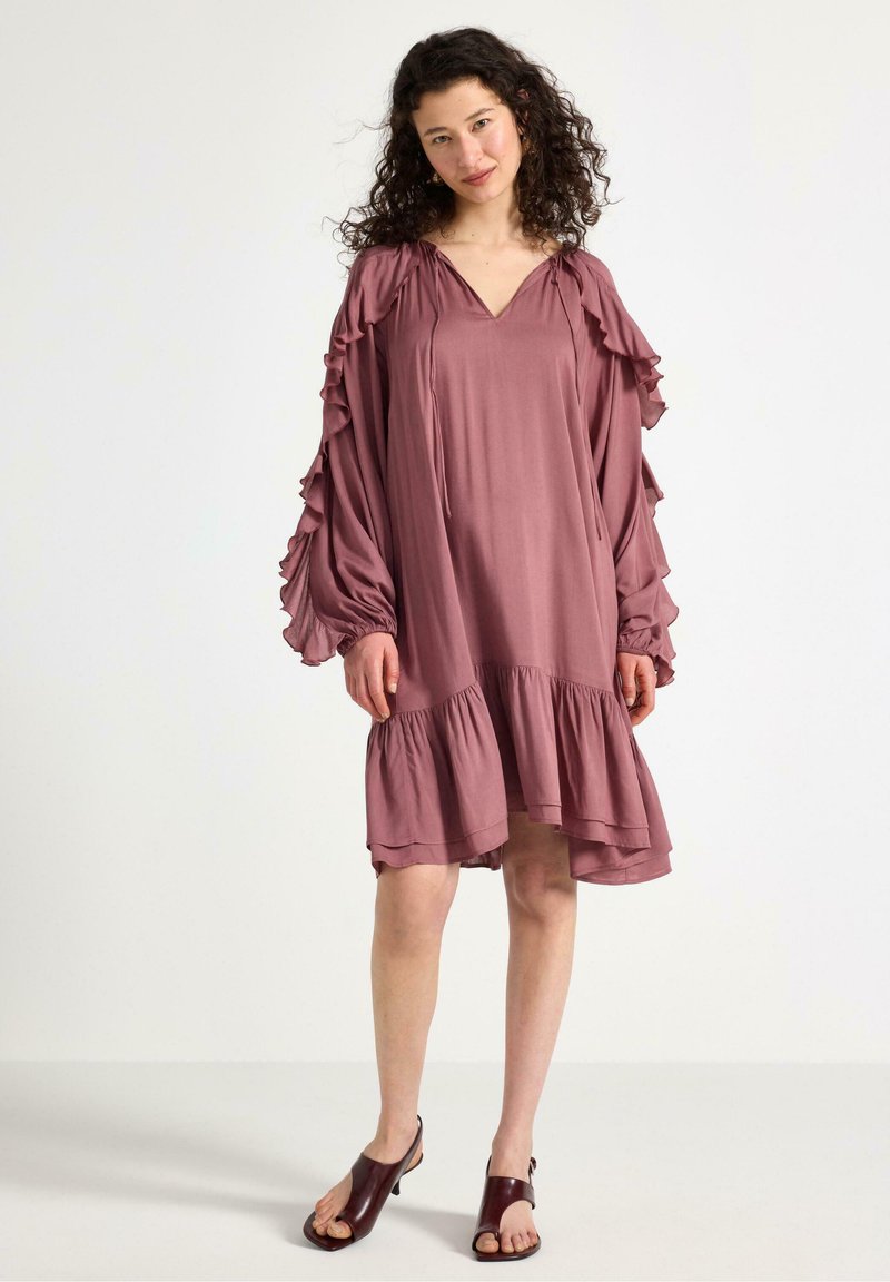 Lös passform, mauve klänning med volangärmar och ett lager på lager-ärmslut. Tillverkad av lätt viktigt material, med V-ringning och rynkade detaljer.