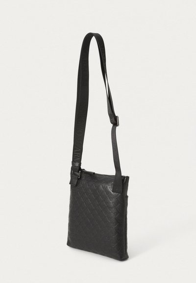 Geantă crossbody din piele neagră cu un model matlasat, curea reglabilă și închidere cu fermoar. Prezintă o textură netedă și un design minimalist.