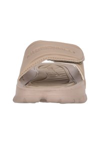 Beige sandle med en vadderad övre rem, texturerad innersula och en flexibel gummisula med en vadderad fotbädd.