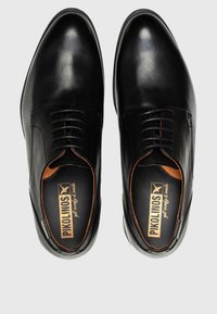 Chaussures en cuir noir avec une finition lisse, bout rond et un design à lacets. Présentent des accents orange et une semelle intérieure rembourrée avec le logo de la marque.