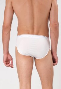 Weiße Baumwollslips mit glatter Textur, niedrig geschnittenem Design und einem kontrastierenden Bund. Verfügt über einen klaren Schnitt und einen minimalistischen Stil.