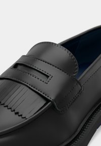 Μαύρα δερμάτινα loafers με υφή στη λουρίδα penny, που διαθέτουν ομαλή επιφάνεια, διακριτικές ραφές και μπλε επένδυση στο εσωτερικό.