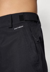 Mustavad veekindlad püksid tekstuuriga kangast. Omavad reguleeritavat vööd ja tõmblukuga taskut, millel on brodeeritud "DRYVENT" logo.