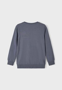 Sweatshirt gris à manches longues, avec des poignets et un ourlet côtelés. Texture lisse, design à col rond, sans motifs ni accents visibles.