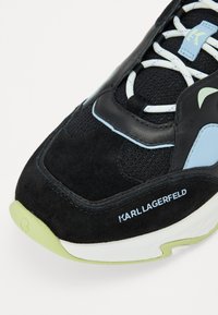 Sneakers din suede negru și plasă, cu accente de culoare albastru deschis, materiale texturate, șirete albe, talpă verde și branding "KARL LAGERFELD".