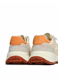 Baskets de couleur claire avec une tige texturée, des accents en suède orange et une semelle en caoutchouc striée avec "HOFF" embossé.