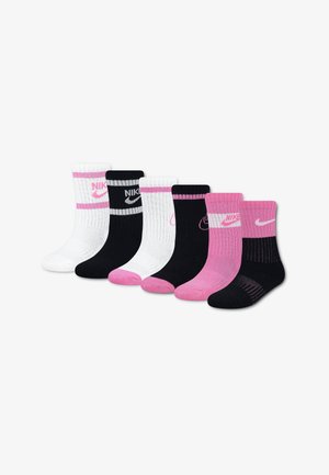 Six paires de chaussettes montantes Nike en blanc, noir et rose, avec des logos contrastants et des accents au talon et aux orteils, disposées en rangée sur un fond blanc.